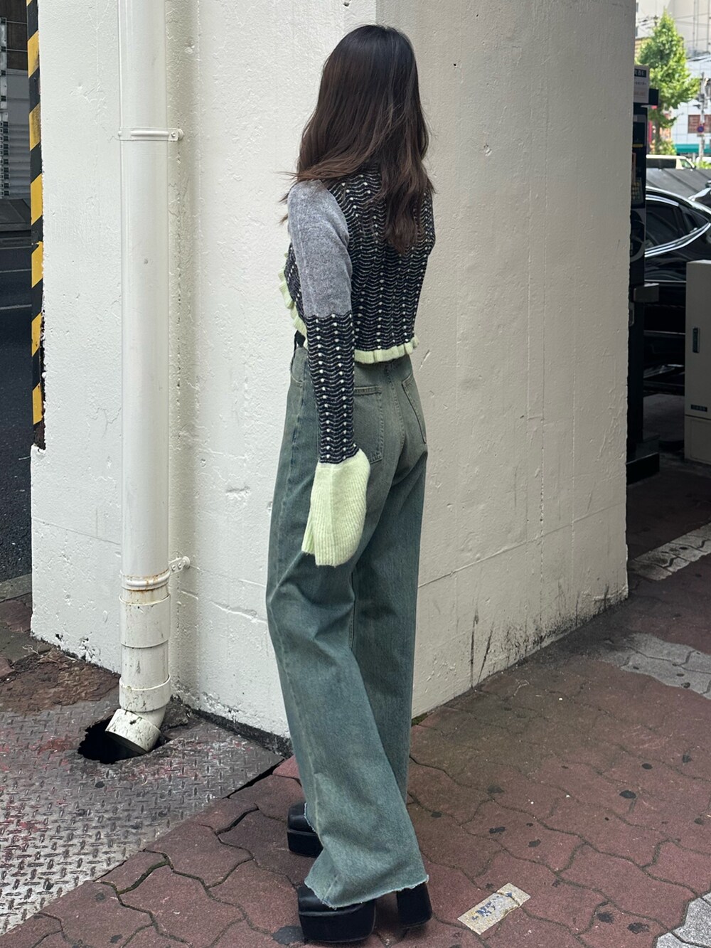 イエロー系のニット/セーター、ブルー系のデニムパンツ、ブラック系のショルダーバッグを着用したレディースの秋コーディネートの2枚目の写真