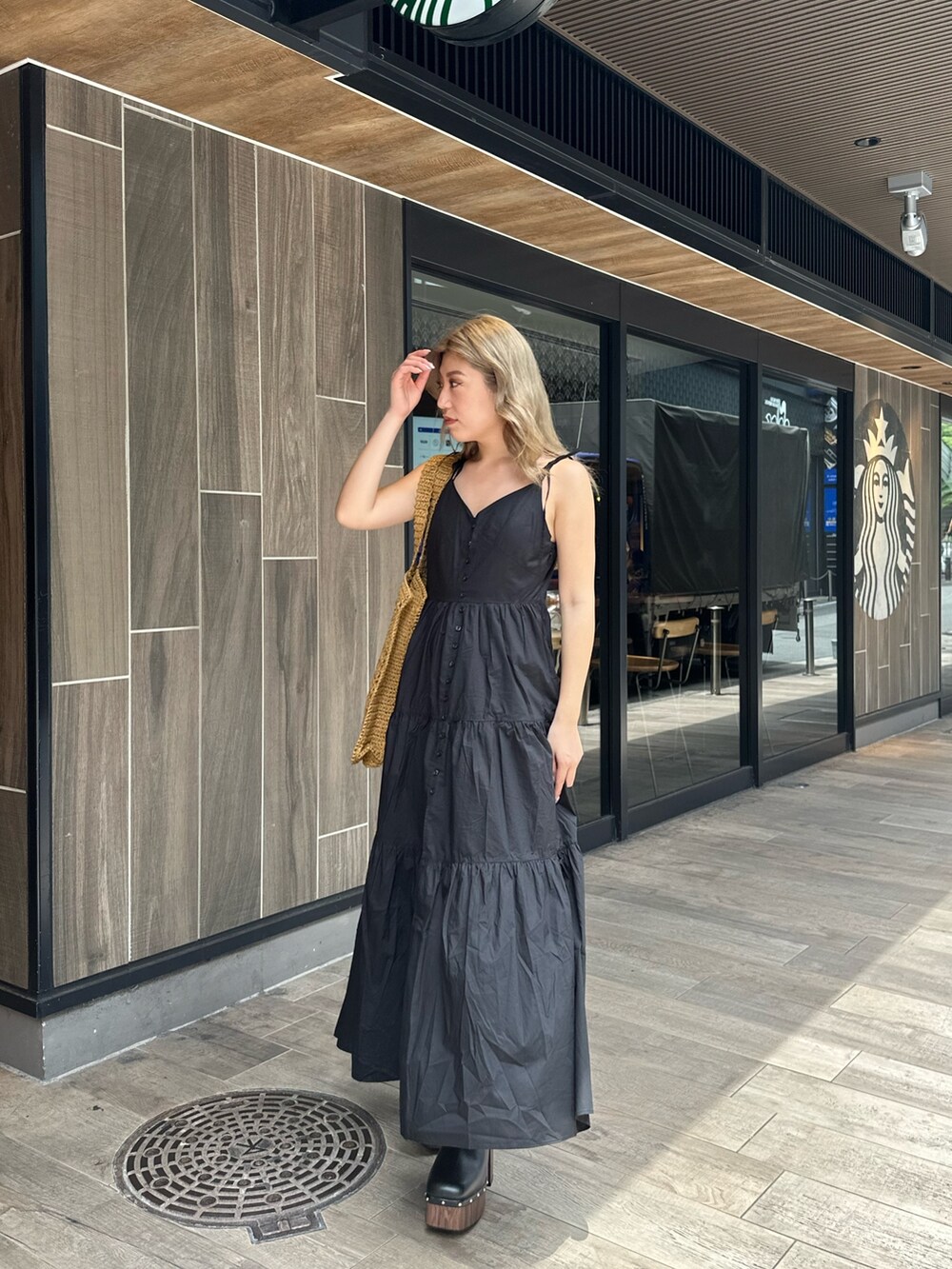 ブラック系のワンピース、ブラック系のサンダル、ベージュ系のトートバッグを着用したレディースの夏コーディネートの2枚目の写真