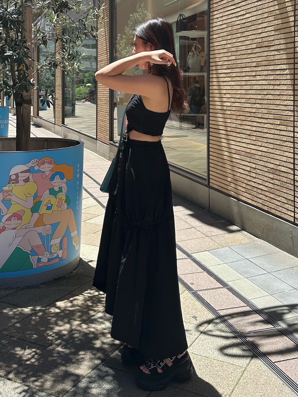 ブラック系のサンダル、ブルー系のショルダーバッグ、ブラック系のワンピースを着用したレディースの夏コーディネートの2枚目の写真