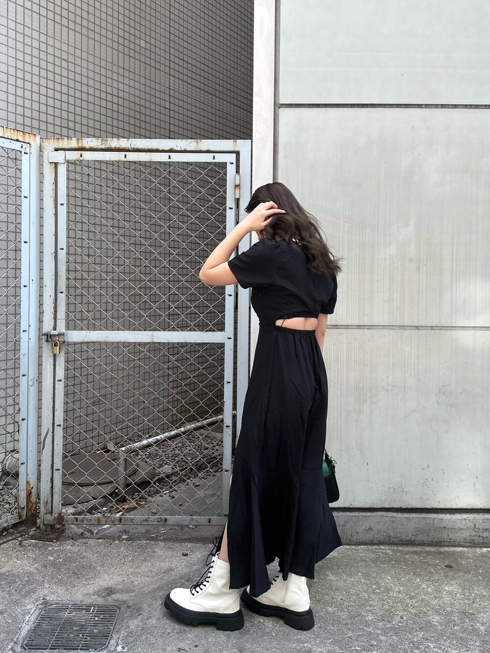 ブラック系のワンピース、ホワイト系のブーツ、ブラック系のショルダーバッグを着用したレディースの春コーディネートの3枚目の写真