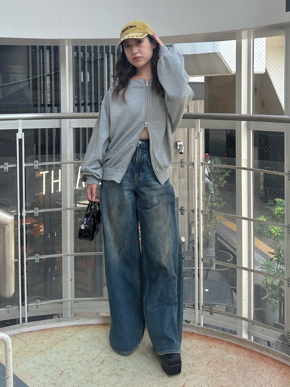 ブルー系のデニムパンツ、グレー系のパーカー、ブラック系のハンドバッグを着用したレディースの秋コーディネートの2枚目の写真