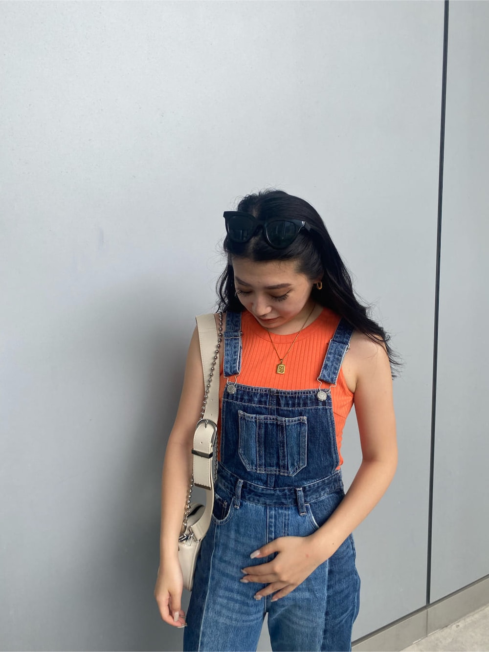 ホワイト系のショルダーバッグ、ブルー系のサロペット/オーバーオール、オレンジ系のタンクトップを着用したレディースの夏コーディネートの3枚目の写真
