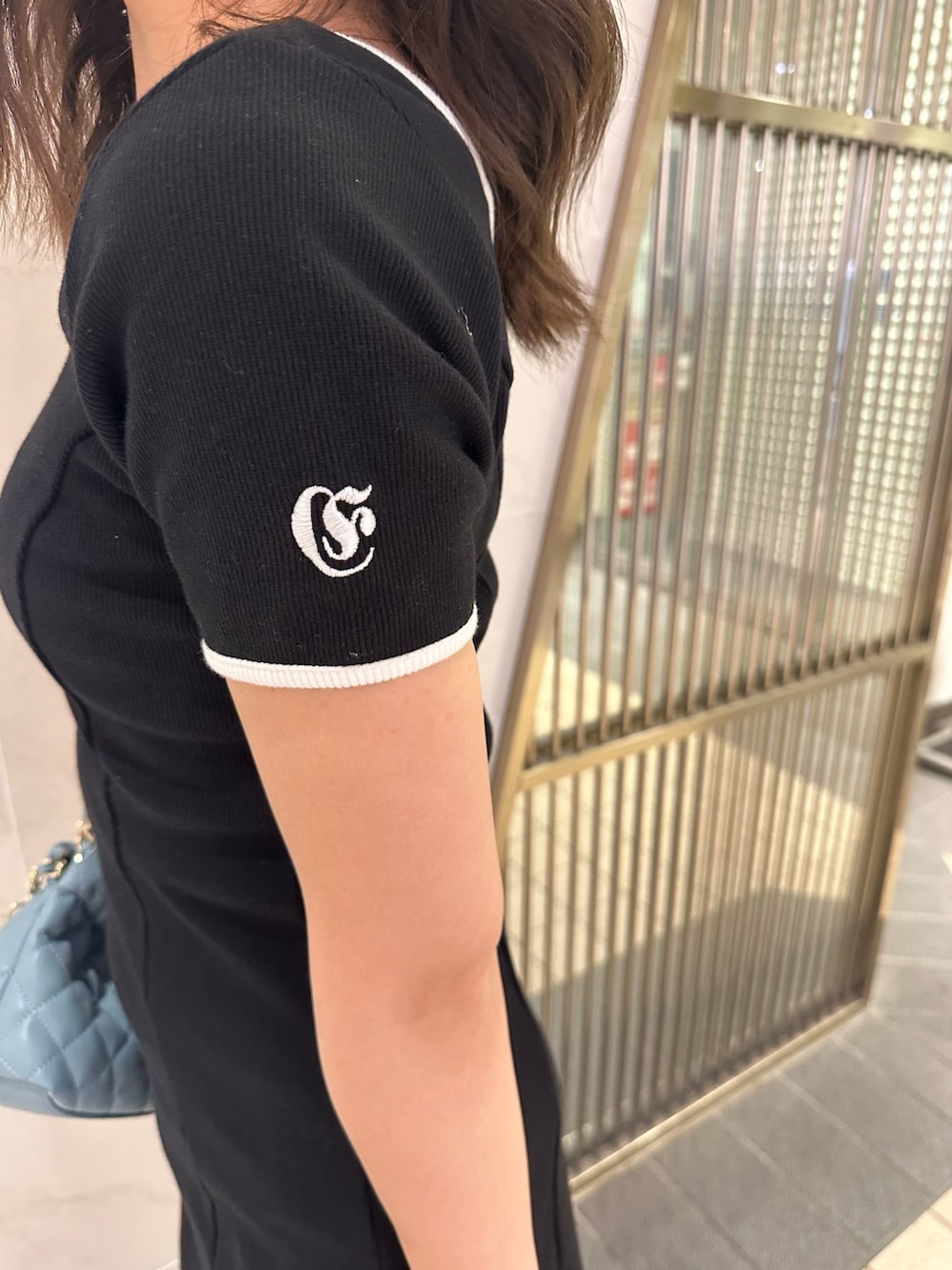 ブルー系のショルダーバッグ、ブラウン系のブーツ、ブラック系のワンピースを着用したレディースの春コーディネートの5枚目の写真