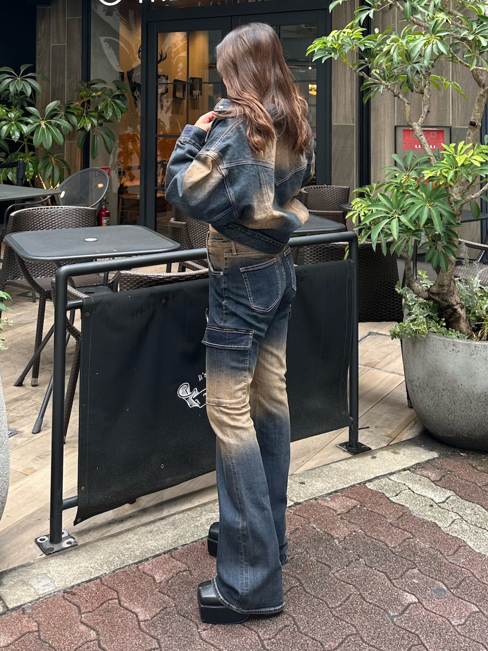 ブルー系のデニムパンツ、ブルー系のデニムジャケット、ブラック系のブーツを着用したレディースの秋コーディネートの2枚目の写真