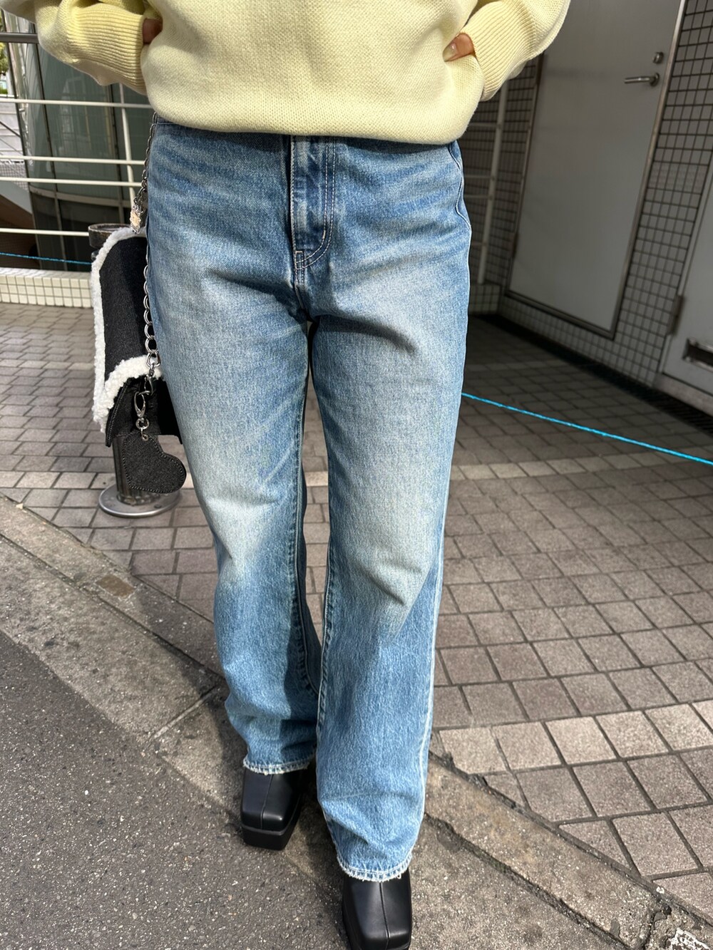 イエロー系のニット/セーター、ブルー系のデニムパンツ、ブラック系のショルダーバッグを着用したレディースの冬コーディネートの6枚目の写真