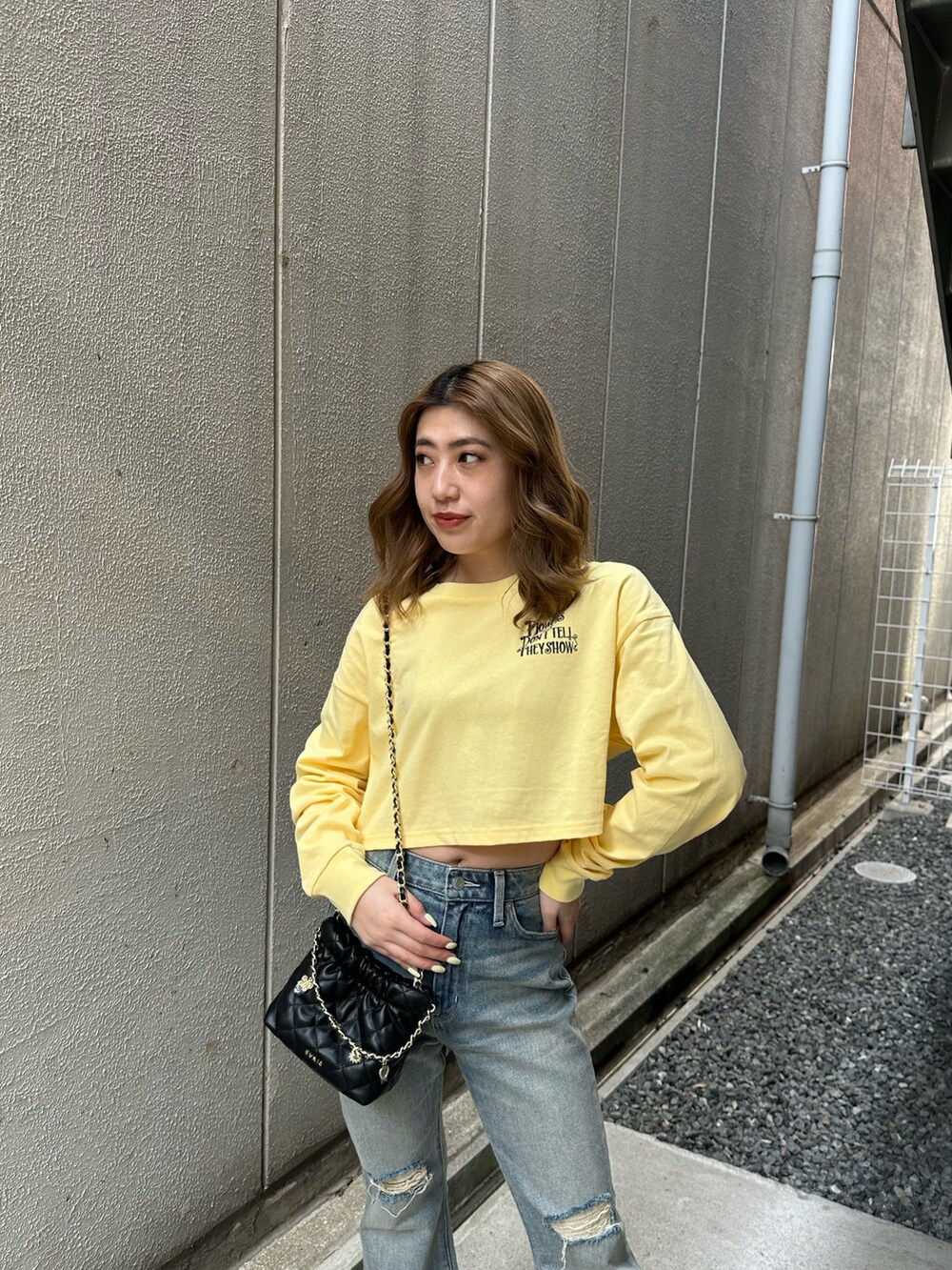 イエロー系のTシャツ/カットソー、ブルー系のデニムパンツ、ブラック系のショルダーバッグを着用したレディースの春コーディネートの4枚目の写真