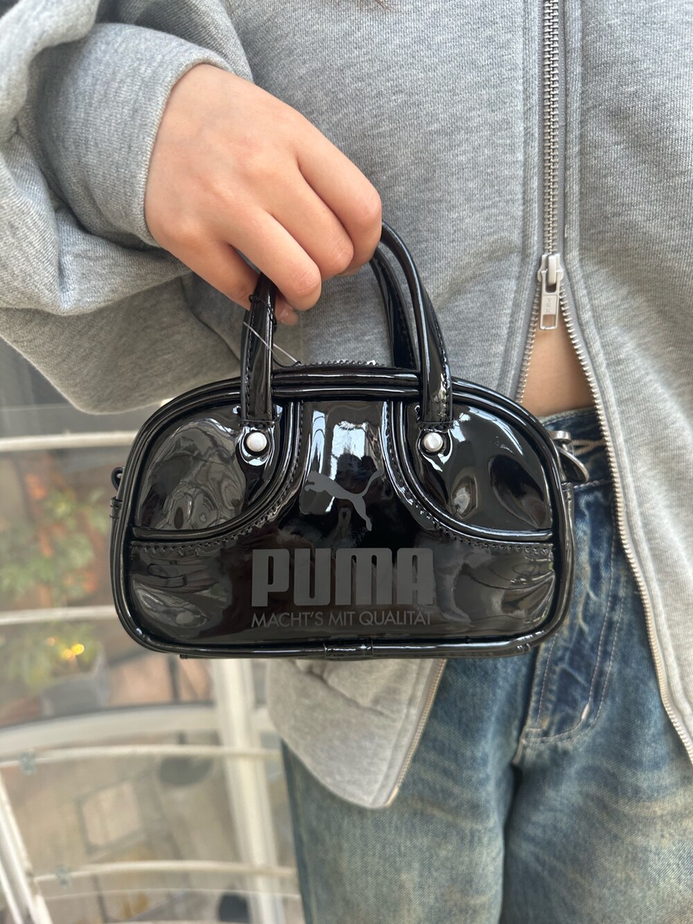 ブルー系のデニムパンツ、グレー系のパーカー、ブラック系のハンドバッグを着用したレディースの秋コーディネートの8枚目の写真