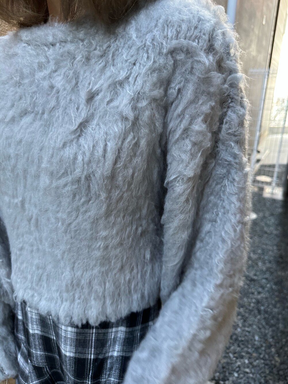 グレー系のニット/セーター、ブラック系のスカート、ブラック系のブーツを着用したレディースの冬コーディネートの6枚目の写真