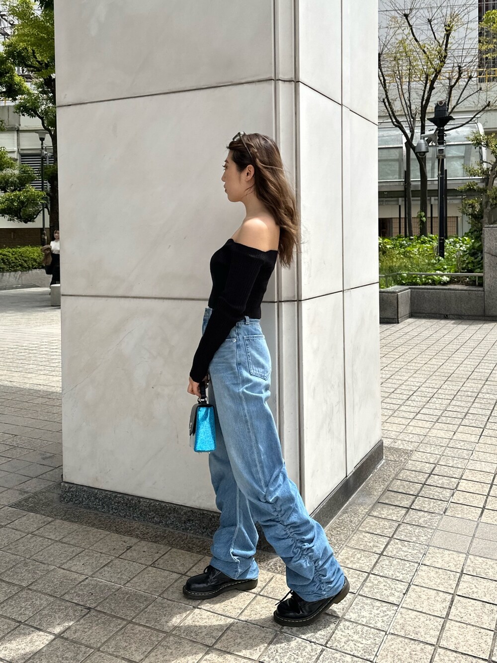 ブルー系のデニムパンツ、ブルー系のショルダーバッグ、ブラック系のニット/セーターを着用したレディースの春コーディネートの2枚目の写真