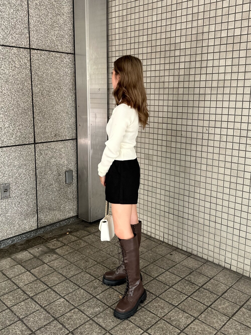 ブラック系のその他パンツ、ホワイト系のショルダーバッグ、ブラウン系のブーツを着用したレディースの夏コーディネートの2枚目の写真