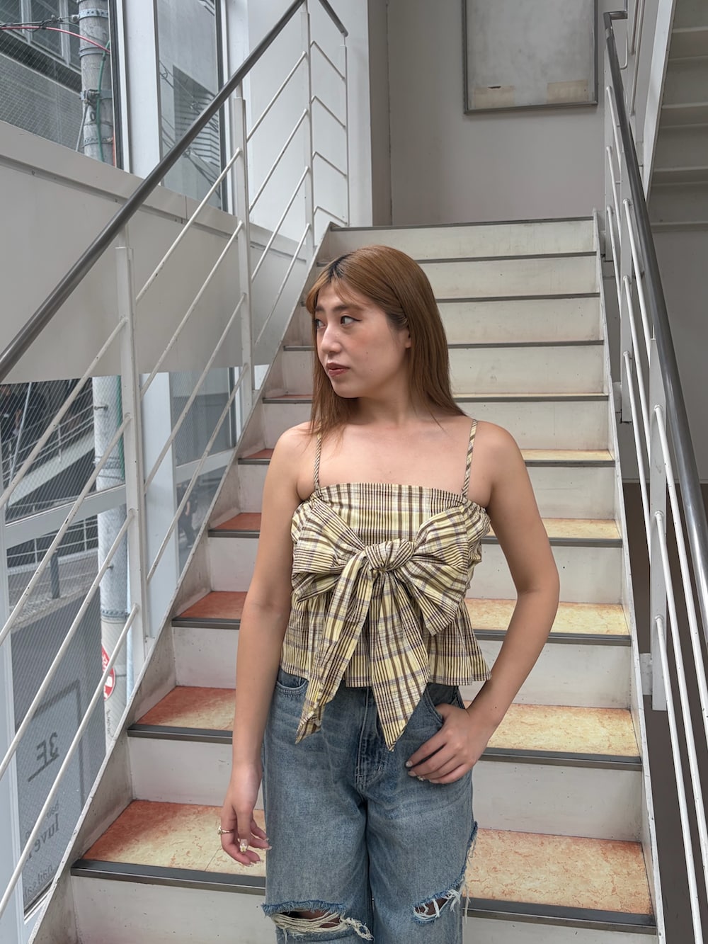 イエロー系のキャミソール、ブルー系のデニムパンツ、ブラック系のブーツを着用したレディースの夏コーディネートの4枚目の写真