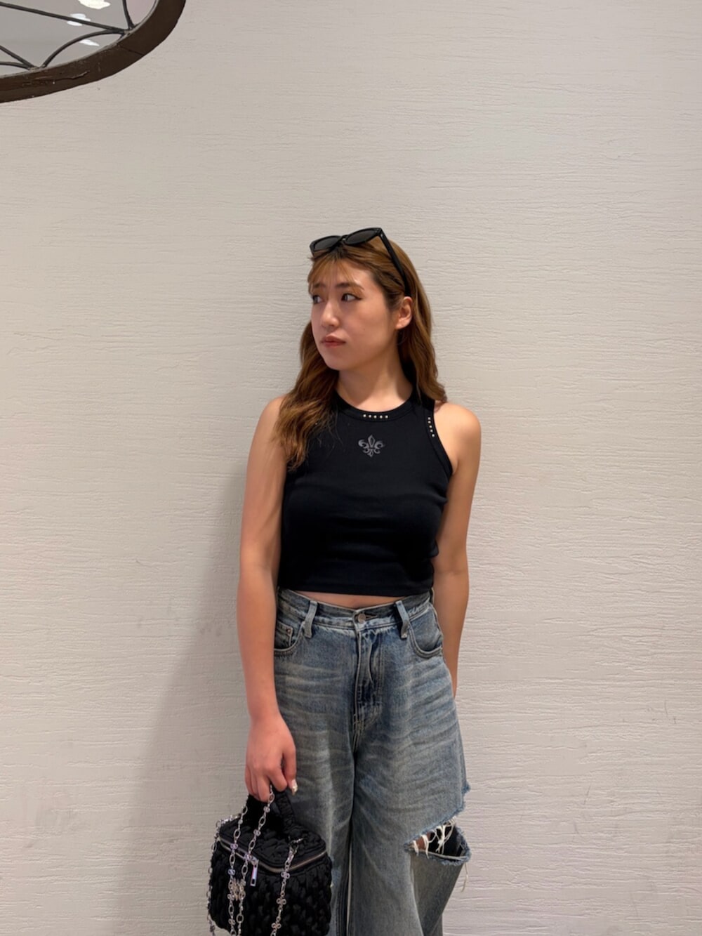 ブルー系のデニムパンツ、ブラック系のショルダーバッグ、シルバー系のサンダルを着用したレディースの夏コーディネートの5枚目の写真