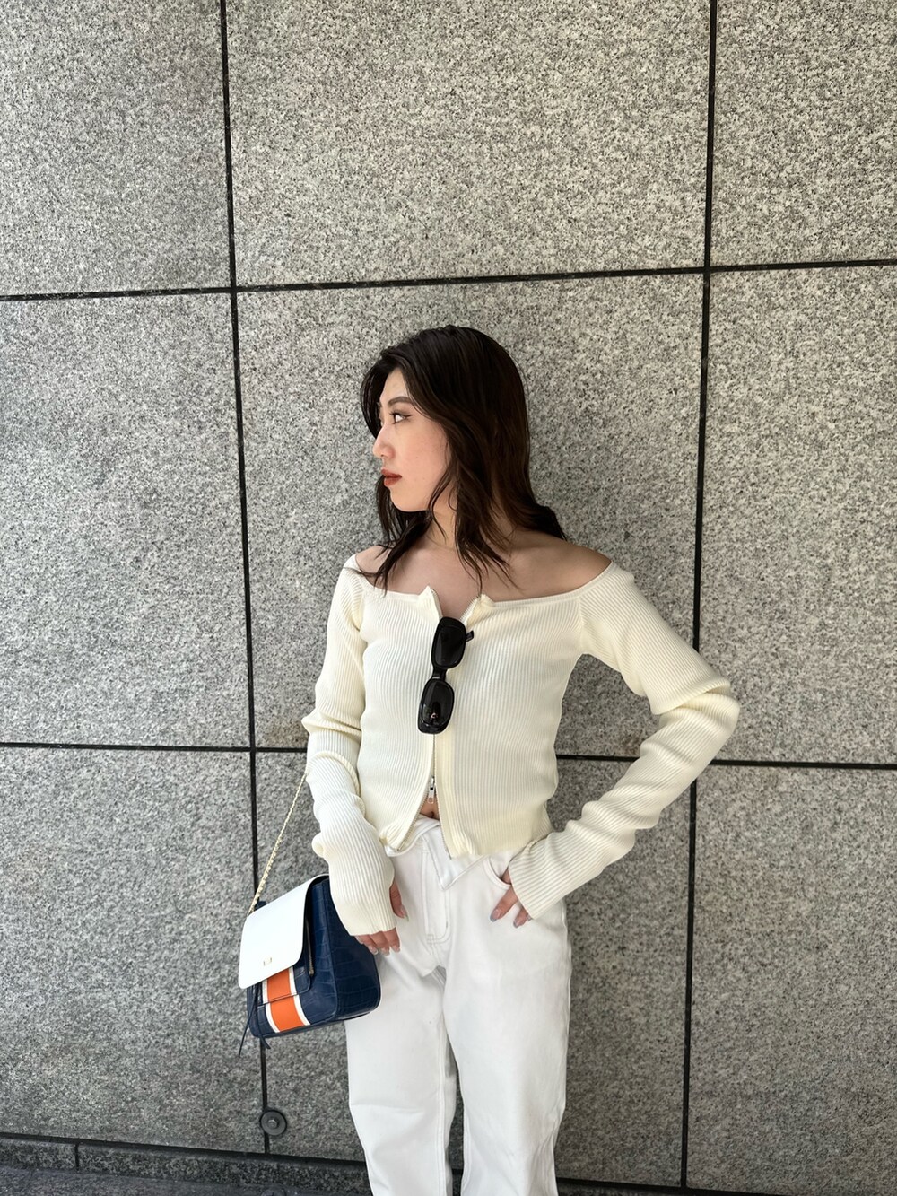 ホワイト系のニット/セーター、ホワイト系のデニムパンツ、ブルー系のショルダーバッグを着用したレディースの春コーディネートの4枚目の写真