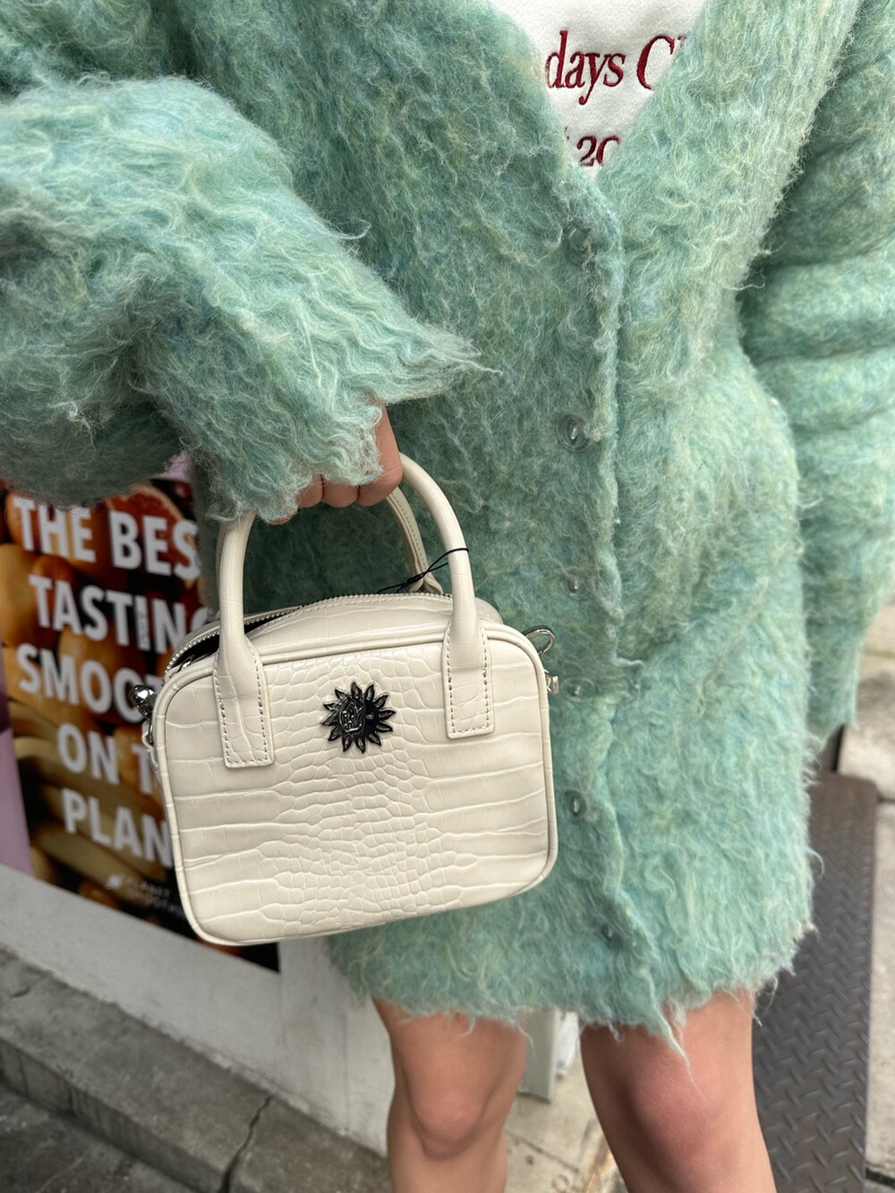 ホワイト系のショルダーバッグ、グリーン系のカーディガン/ボレロ、ブラック系のブーツを着用したレディースの冬コーディネートの6枚目の写真