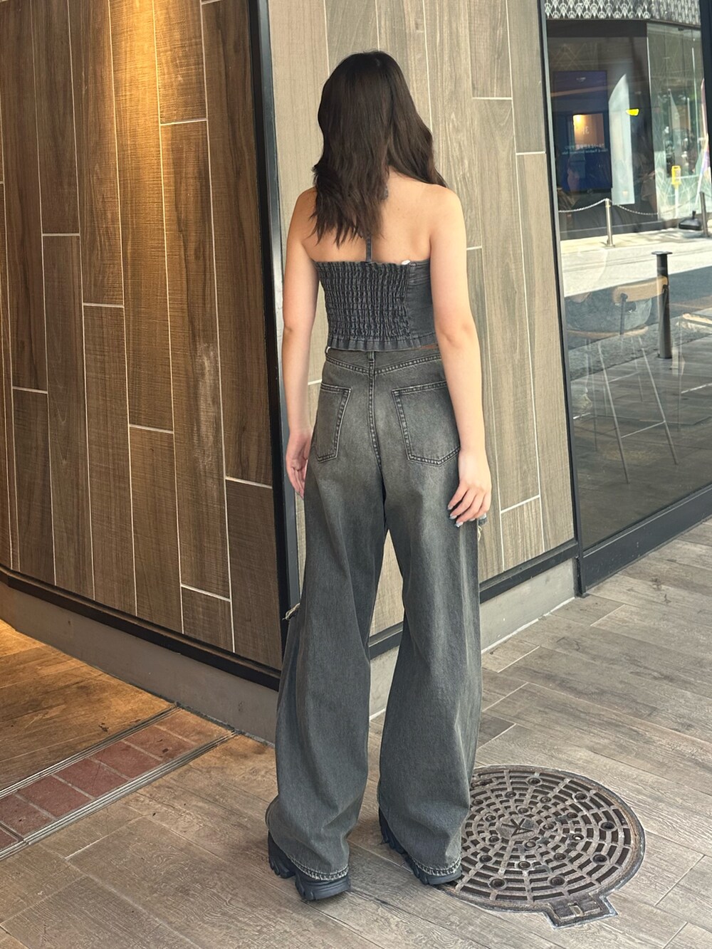 ブラック系のデニムパンツ、ブラック系のキャミソール、ブラック系のサンダルを着用したレディースの夏コーディネートの4枚目の写真