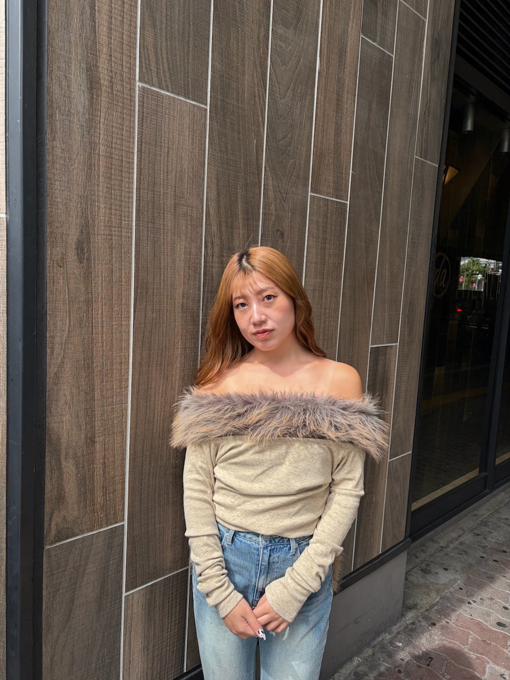 ブルー系のデニムパンツ、ベージュ系のTシャツ/カットソー、ブラック系のブーツを着用したレディースの秋コーディネートの4枚目の写真