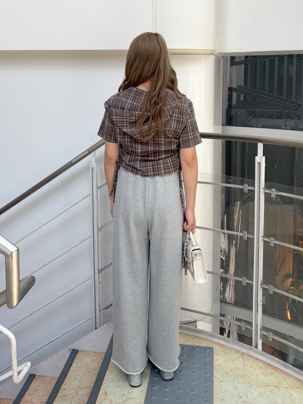 シルバー系のサンダル、グレー系のスウェットパンツ、ホワイト系のショルダーバッグを着用したレディースの夏コーディネートの3枚目の写真