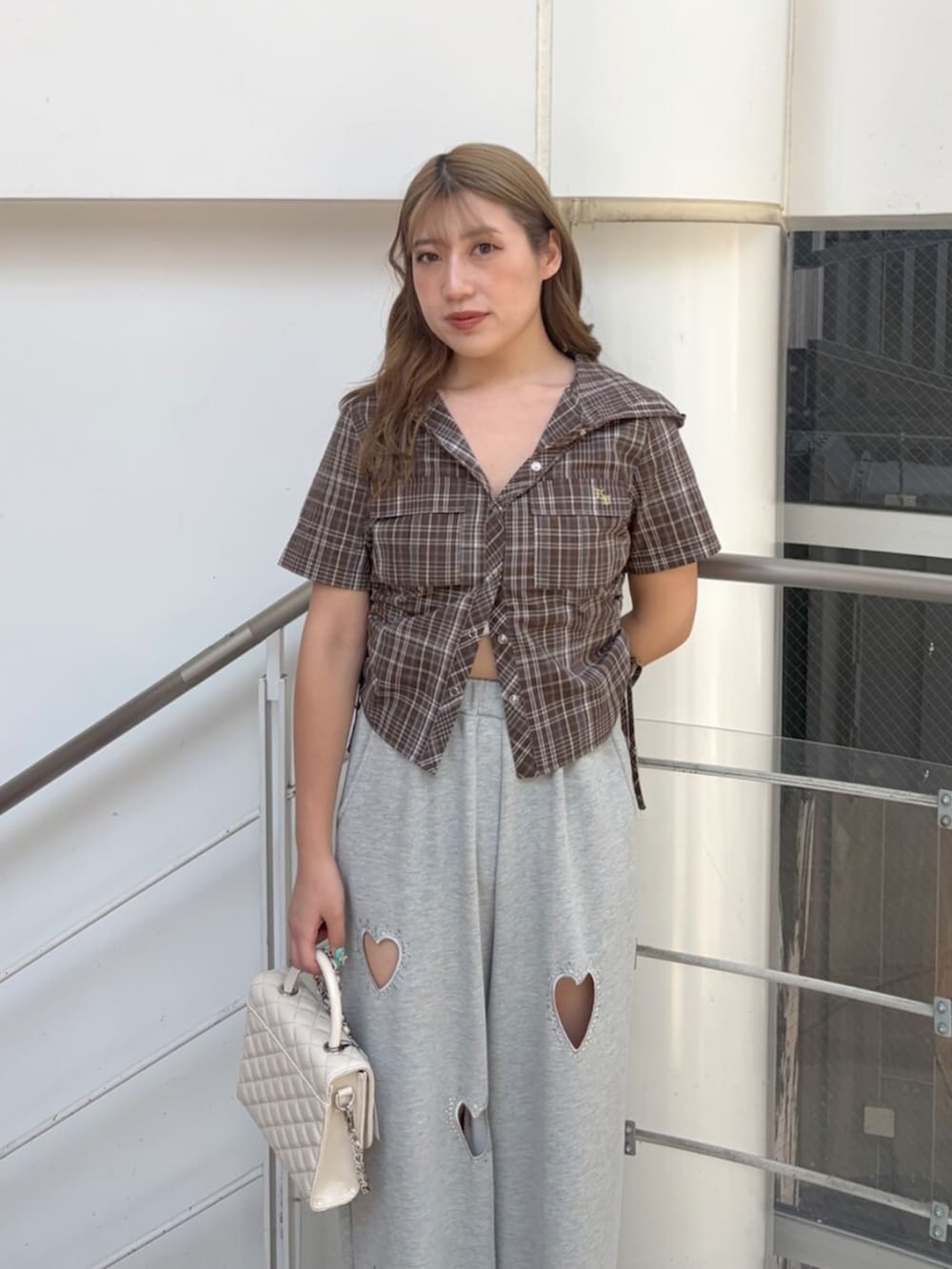 シルバー系のサンダル、グレー系のスウェットパンツ、ホワイト系のショルダーバッグを着用したレディースの夏コーディネートの4枚目の写真
