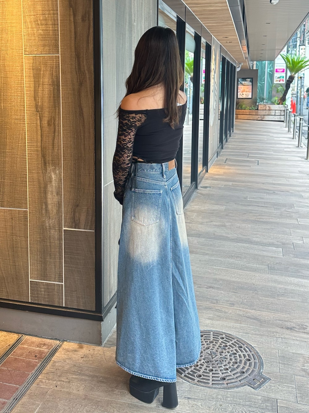 ブルー系のデニムスカート、ブラック系のTシャツ/カットソー、ブラック系のブーツを着用したレディースの秋コーディネートの2枚目の写真