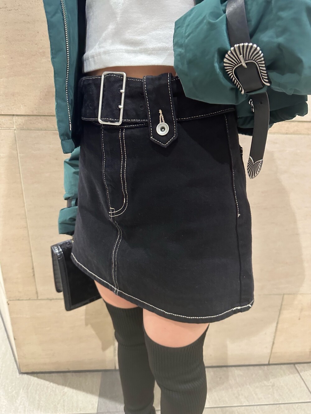 ブルー系のデニムスカート、ホワイト系のTシャツ/カットソー、グリーン系のダウンジャケット/コートを着用したレディースの秋コーディネートの6枚目の写真