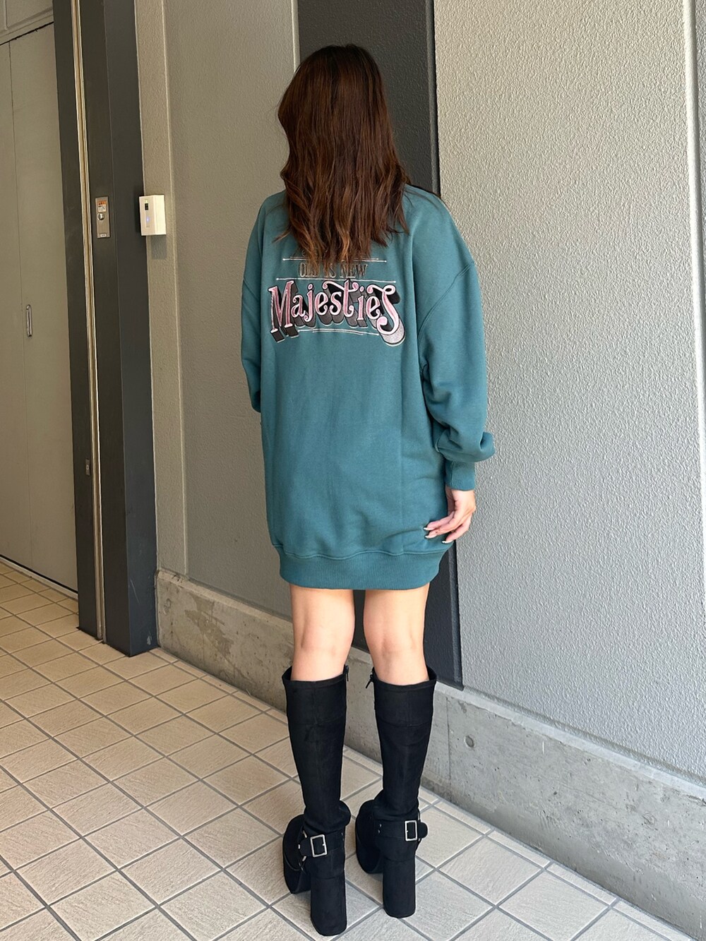 ブルー系のスウェット、ブラック系のブーツ、ブルー系のデニムパンツを着用したレディースの秋コーディネートの3枚目の写真