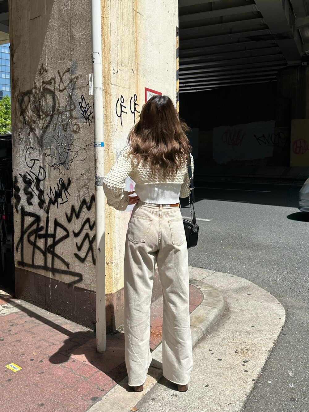 ベージュ系のデニムパンツ、ブラック系のサンダル、ホワイト系のニット/セーターを着用したレディースの春コーディネートの3枚目の写真