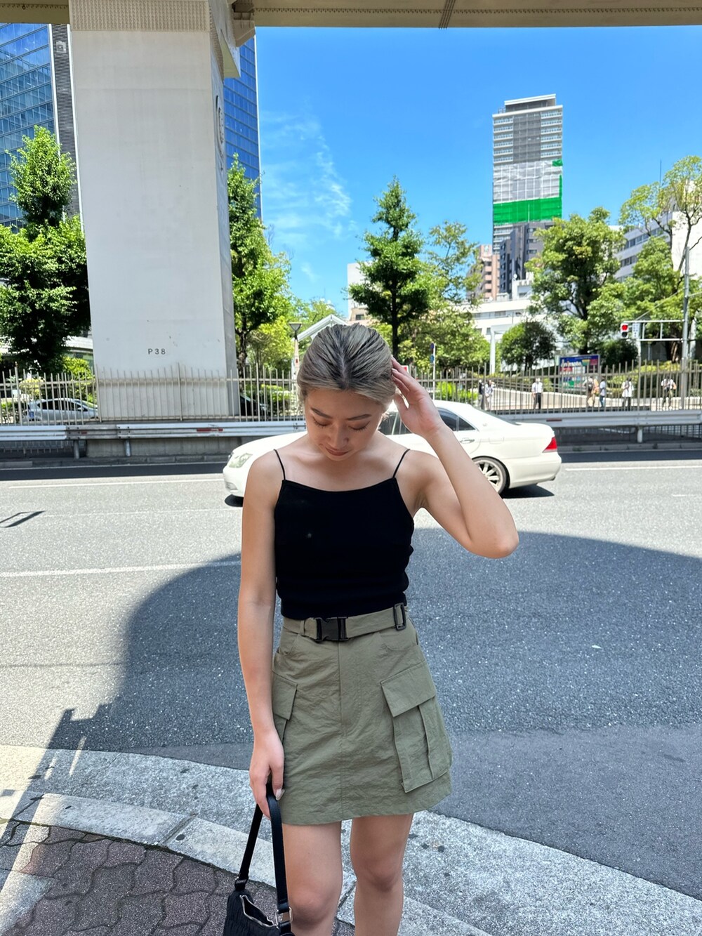 グリーン系のスカート、ブラック系のキャミソール、ブラック系のハンドバッグを着用したレディースの夏コーディネートの4枚目の写真