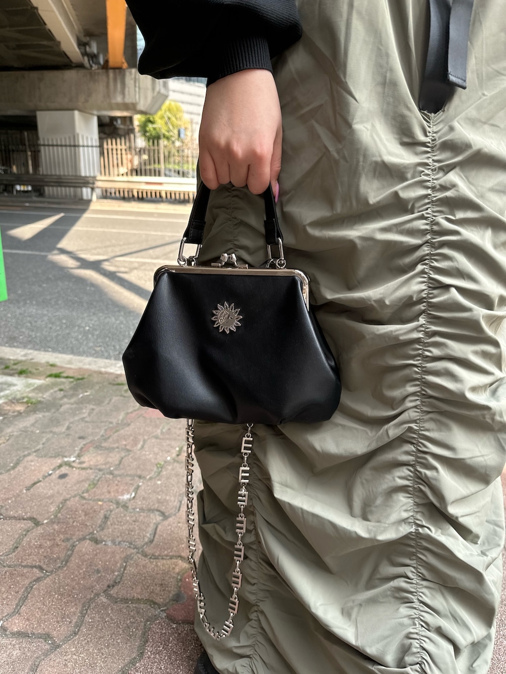 ベージュ系のスカート、ブラック系のカーディガン/ボレロ、ブラック系のショルダーバッグを着用したレディースの春コーディネートの7枚目の写真