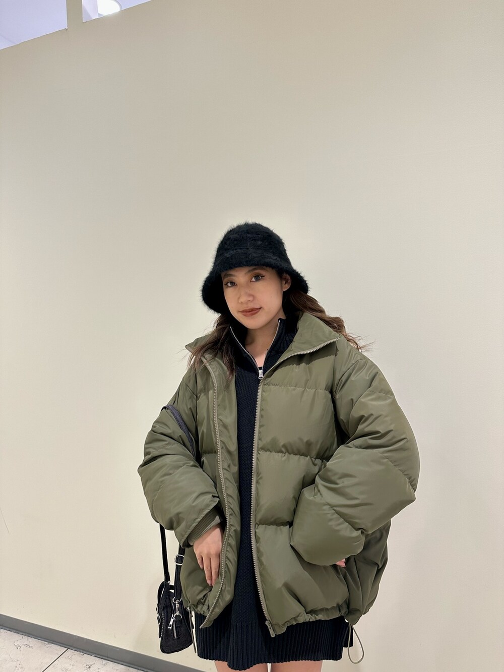 ブラック系のブーツ、ブラック系のニット/セーター、グリーン系のダウンジャケット/コートを着用したレディースの冬コーディネートの5枚目の写真