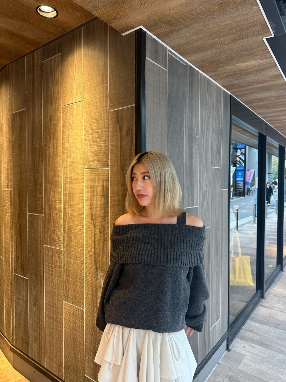 グレー系のワンピース、ホワイト系のスカート、ブラック系のブーツを着用したレディースの秋コーディネートの6枚目の写真