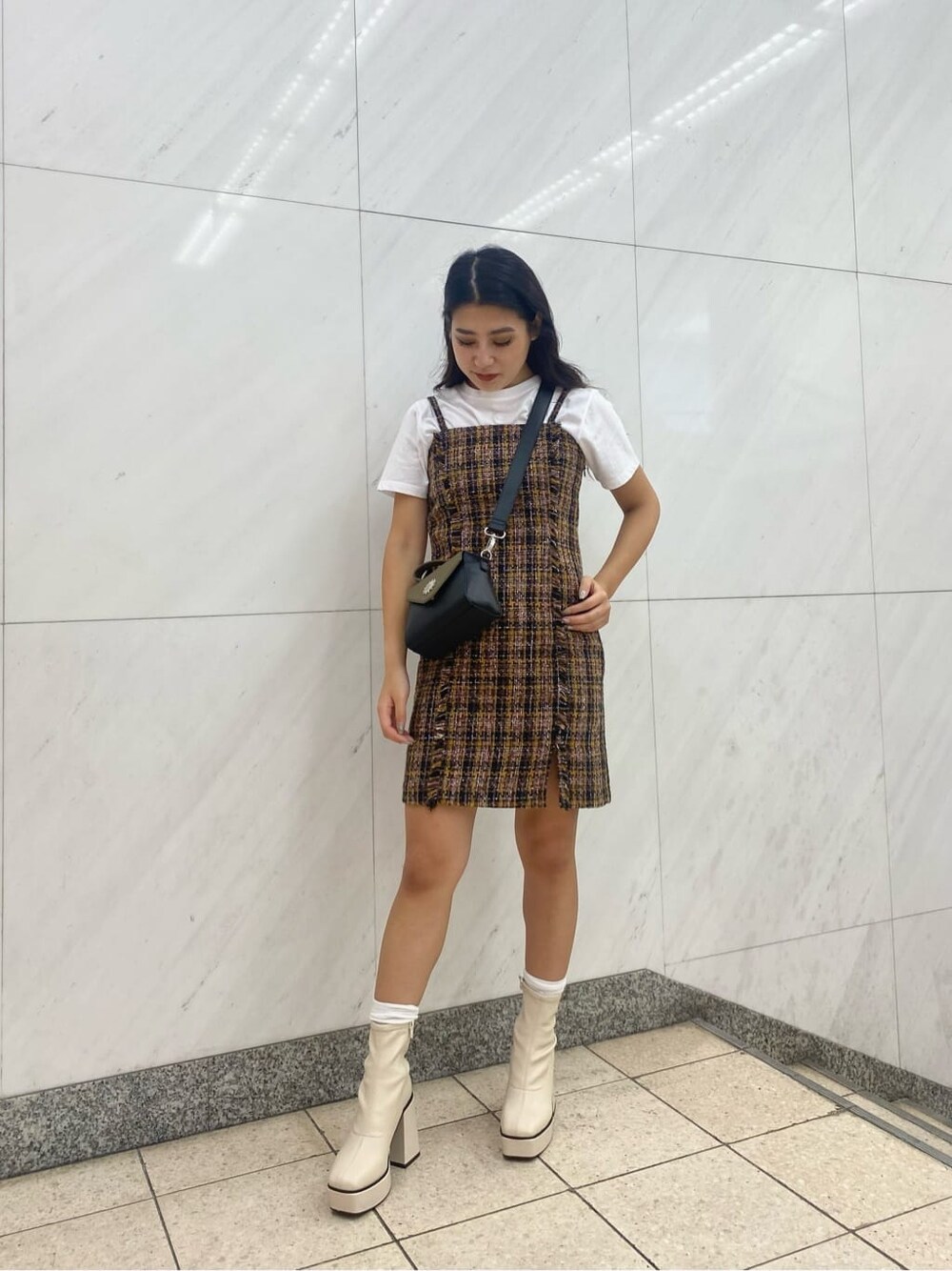 ホワイト系のブーツ、イエロー系のジャンパースカート、ブラック系のショルダーバッグを着用したレディースの夏コーディネートの2枚目の写真