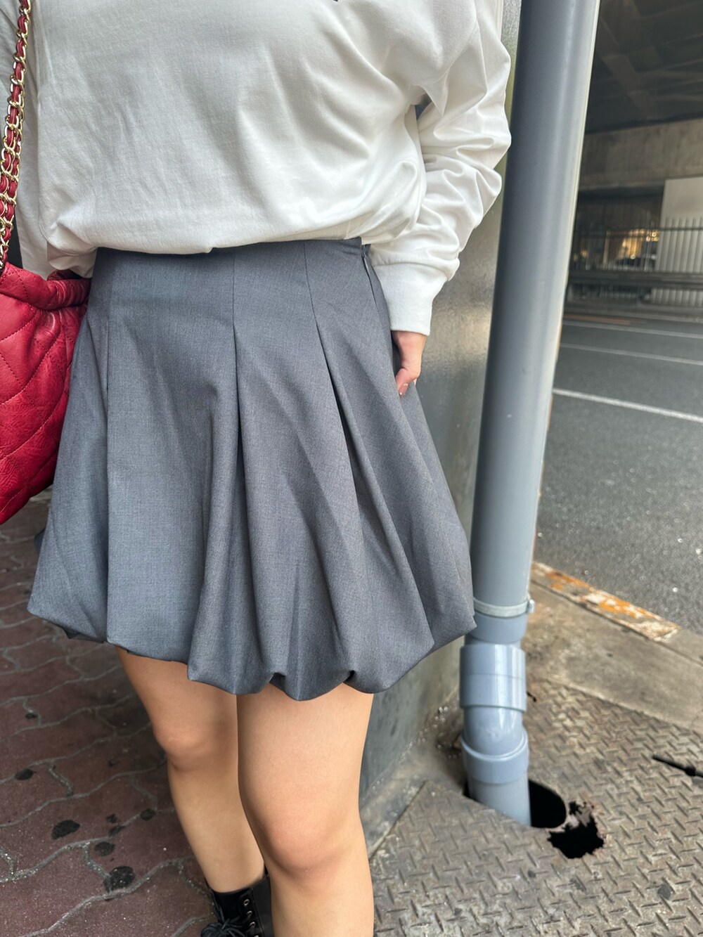 ホワイト系のTシャツ/カットソー、グレー系のスカート、ブラック系のブーツを着用したレディースの秋コーディネートの8枚目の写真