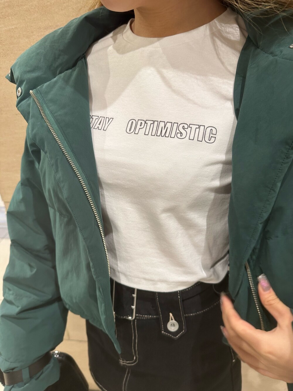 ブルー系のデニムスカート、ホワイト系のTシャツ/カットソー、グリーン系のダウンジャケット/コートを着用したレディースの秋コーディネートの5枚目の写真