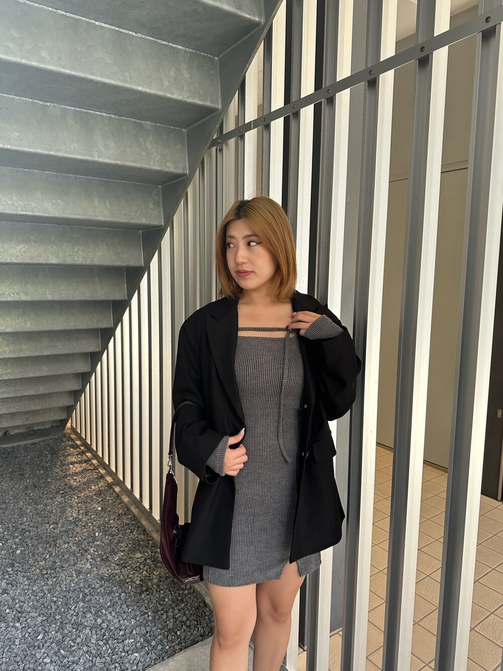 グレー系のワンピース、ブラック系のテーラードジャケット、レッド系のパンプスを着用したレディースの秋コーディネートの5枚目の写真