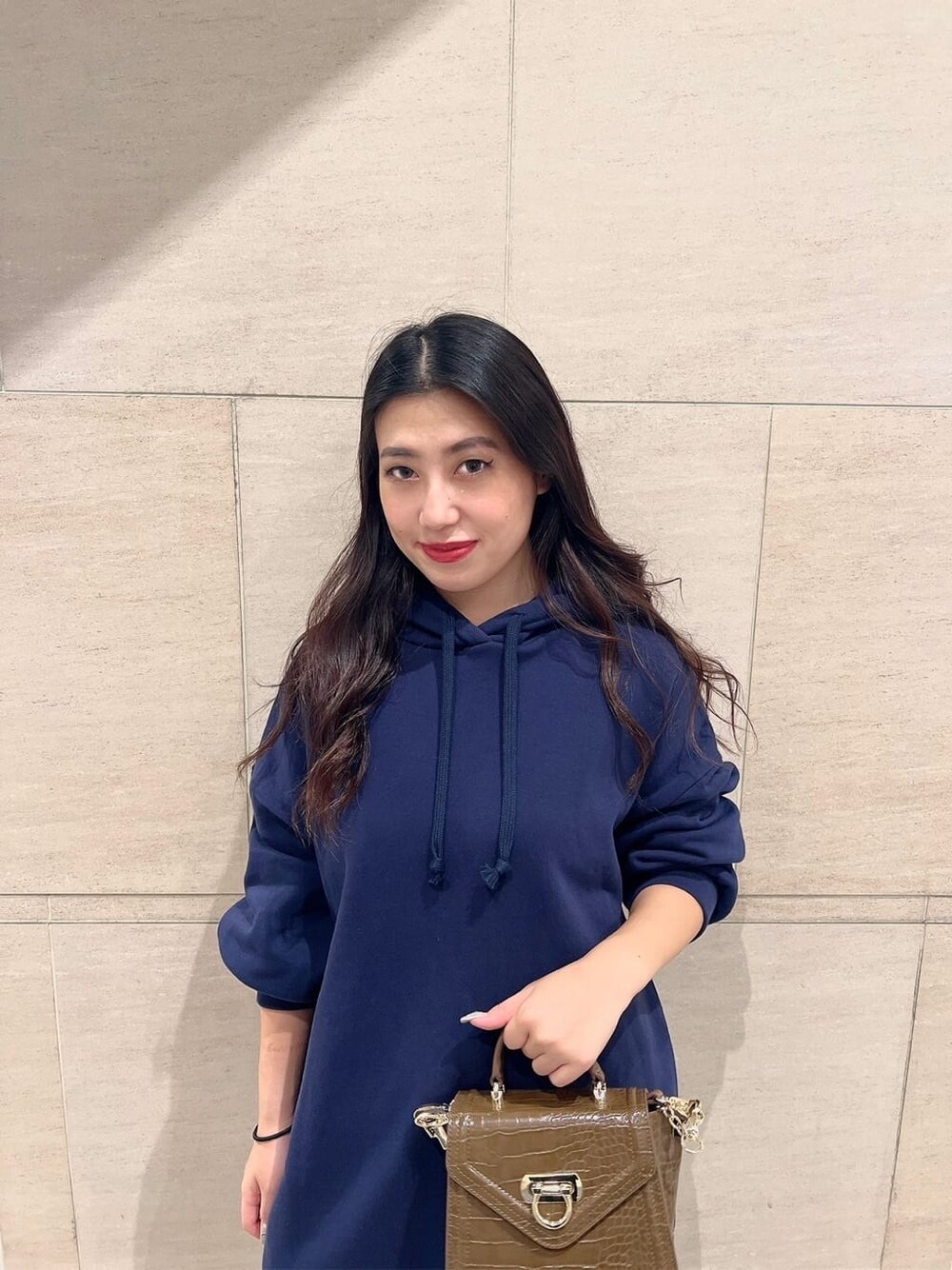 ブラック系のブーツ、ブラウン系のハンドバッグ、ブルー系のパーカーを着用したレディースの秋コーディネートの4枚目の写真