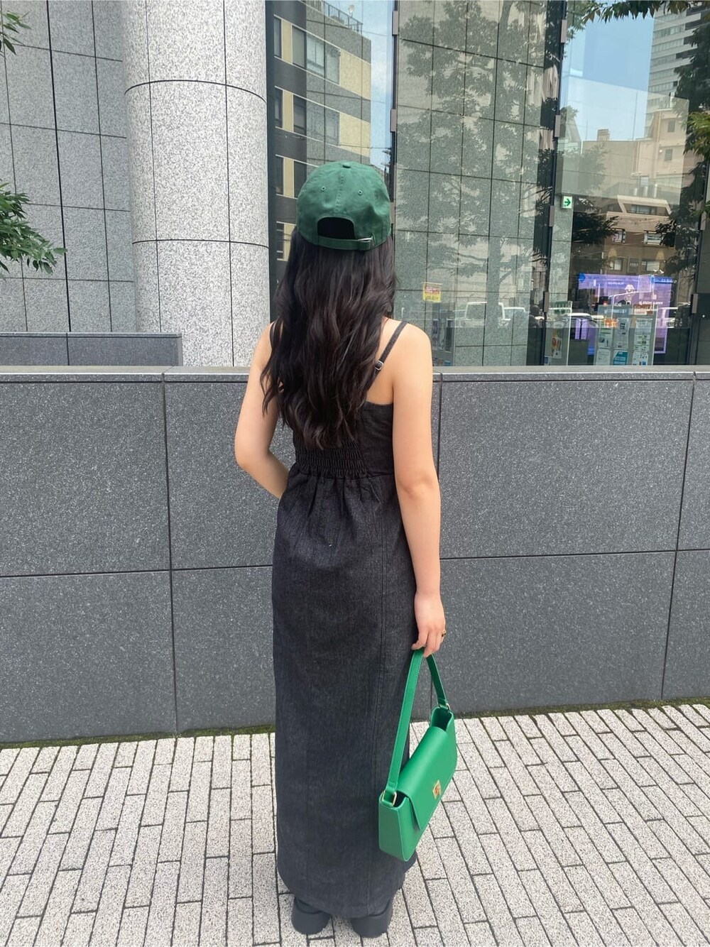 ブラック系のワンピース、グリーン系のショルダーバッグ、ブラック系のブーツを着用したレディースの夏コーディネートの3枚目の写真