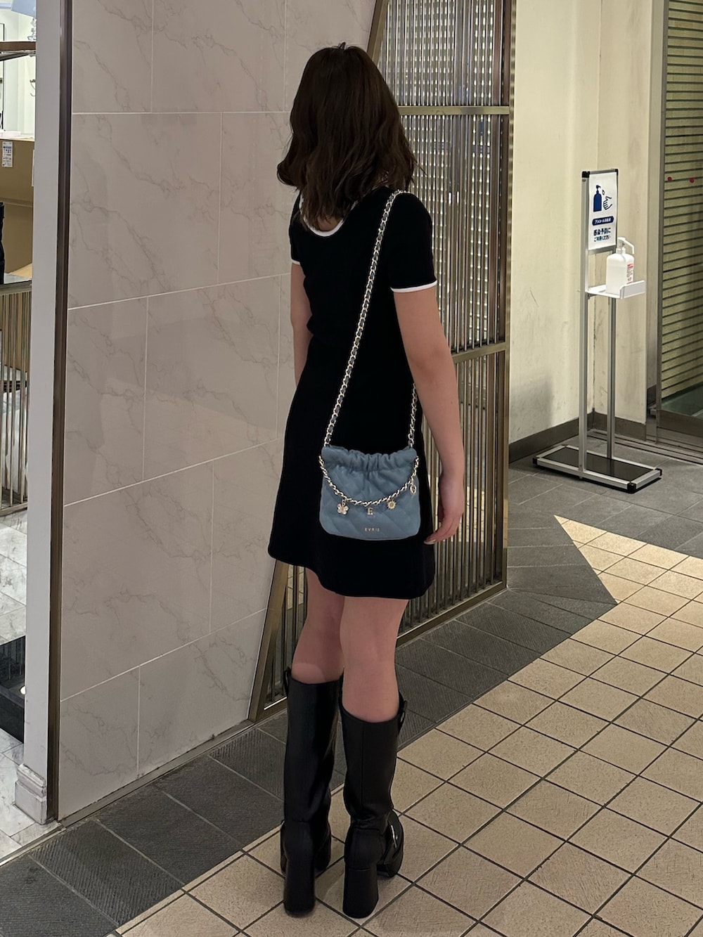 ブルー系のショルダーバッグ、ブラウン系のブーツ、ブラック系のワンピースを着用したレディースの春コーディネートの3枚目の写真