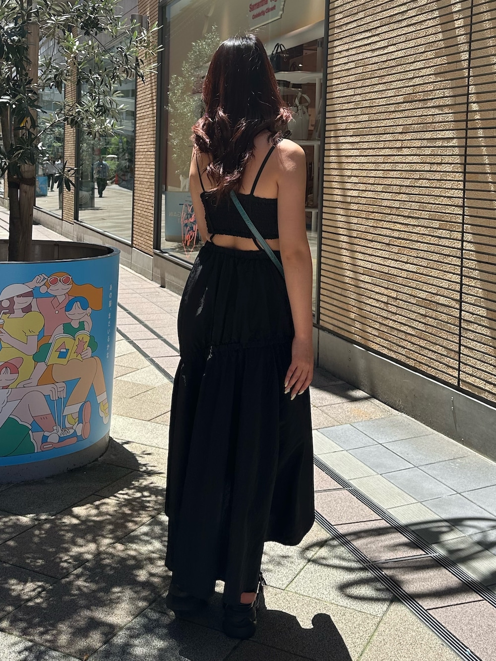 ブラック系のサンダル、ブルー系のショルダーバッグ、ブラック系のワンピースを着用したレディースの夏コーディネートの3枚目の写真