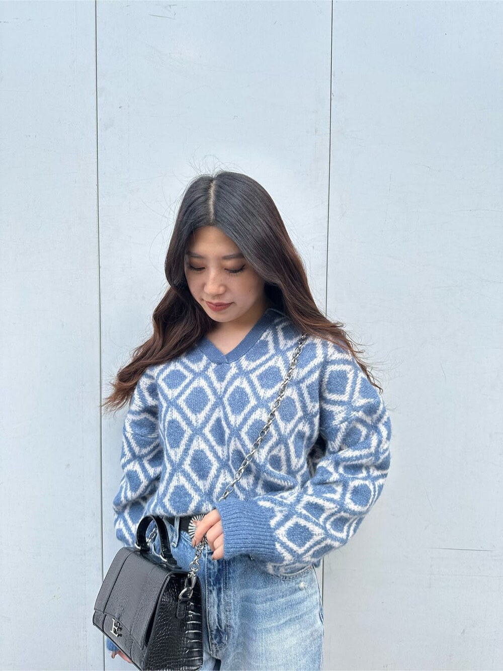 ブラック系のブーツ、ブルー系のニット/セーター、ブルー系のデニムパンツを着用したレディースの秋コーディネートの3枚目の写真