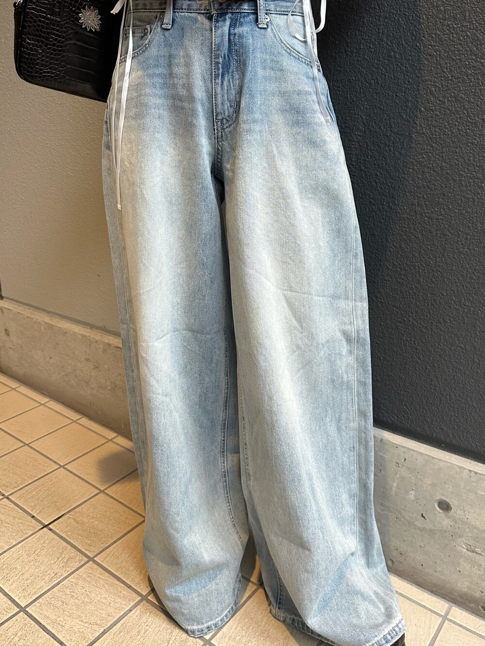 ブルー系のデニムパンツ、ホワイト系のTシャツ/カットソー、ブラック系のショルダーバッグを着用したレディースの春コーディネートの6枚目の写真