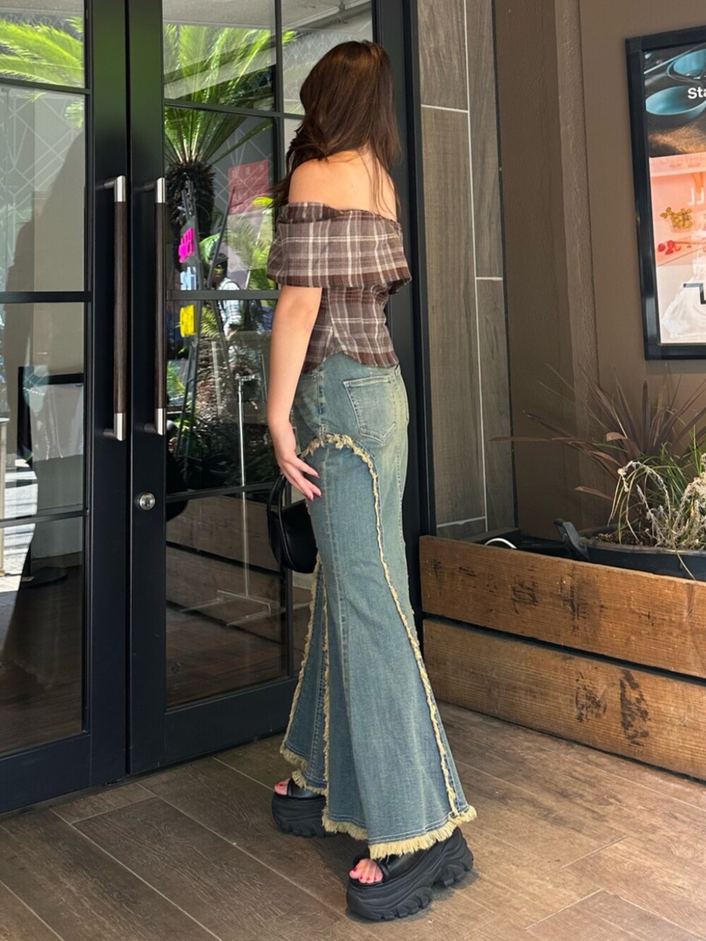 ブラック系のハンドバッグ、ブラック系のサンダル、ブルー系のデニムスカートを着用したレディースの夏コーディネートの2枚目の写真