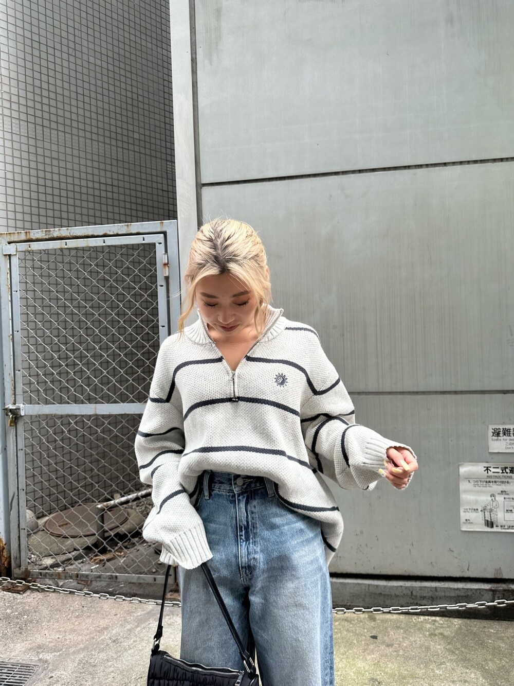 ブラック系のデニムパンツ、ブラック系のハンドバッグ、その他のニット/セーターを着用したレディースの夏コーディネートの4枚目の写真