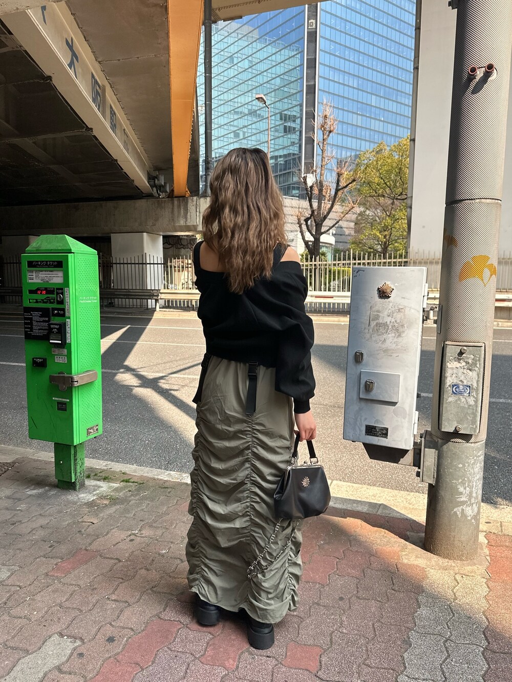 ベージュ系のスカート、ブラック系のカーディガン/ボレロ、ブラック系のショルダーバッグを着用したレディースの春コーディネートの3枚目の写真