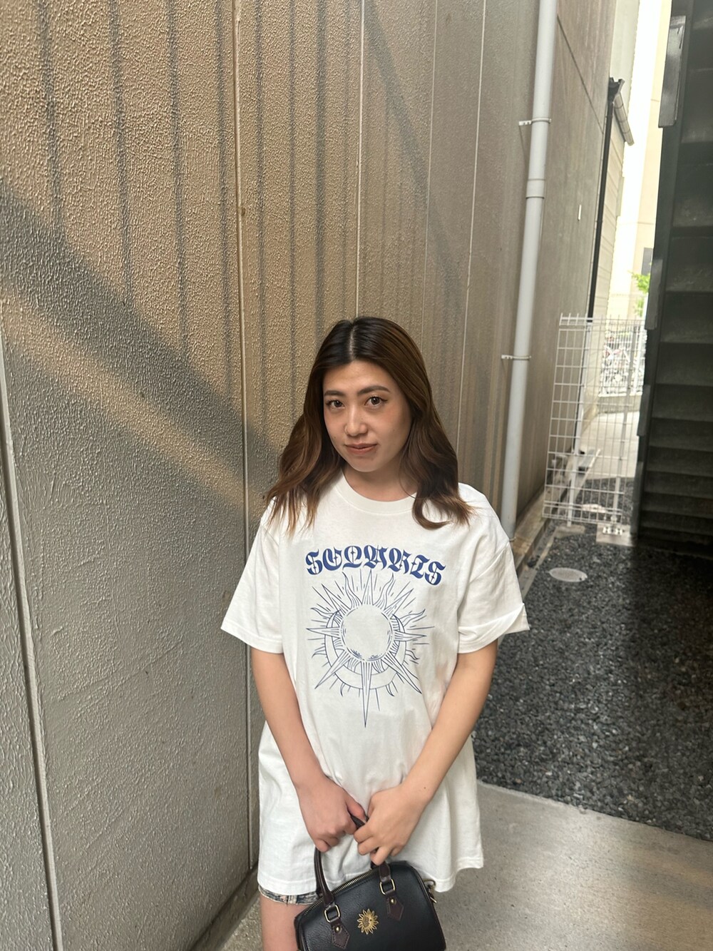 ホワイト系のTシャツ/カットソー、ブラック系のショルダーバッグ、ブラウン系のブーツを着用したレディースの夏コーディネートの4枚目の写真