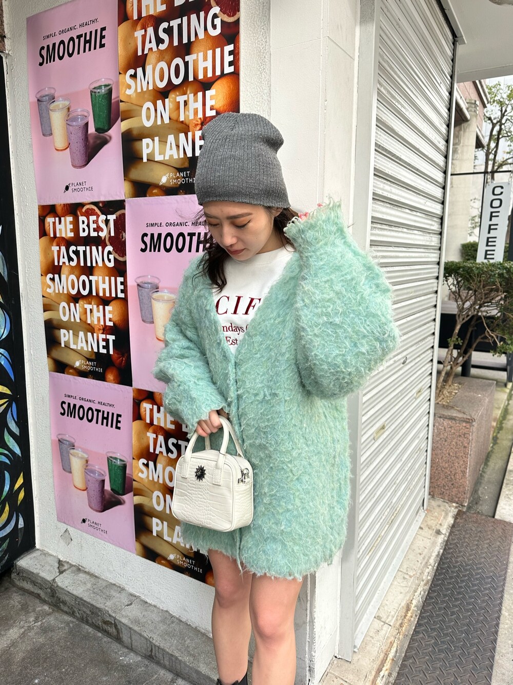 ホワイト系のショルダーバッグ、グリーン系のカーディガン/ボレロ、ブラック系のブーツを着用したレディースの冬コーディネートの3枚目の写真