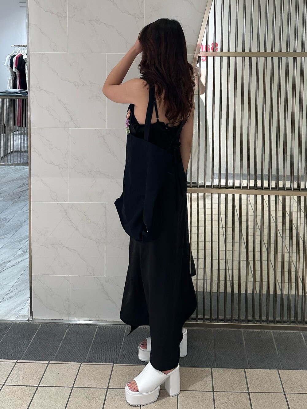 ブラック系のワンピース、ブラック系のトートバッグ、ホワイト系のサンダルを着用したレディースの夏コーディネートの3枚目の写真