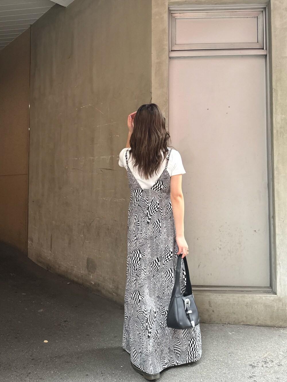 ブラック系のワンピース、ホワイト系のTシャツ/カットソー、ブラック系のハンドバッグを着用したレディースの春コーディネートの3枚目の写真