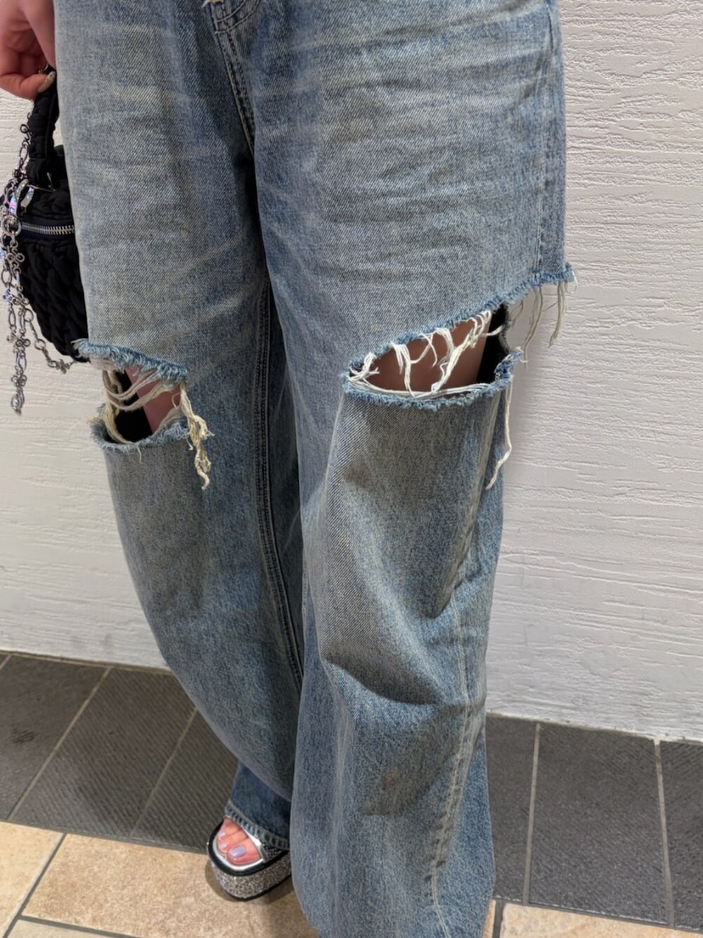 ブルー系のデニムパンツ、ブラック系のショルダーバッグ、シルバー系のサンダルを着用したレディースの夏コーディネートの8枚目の写真