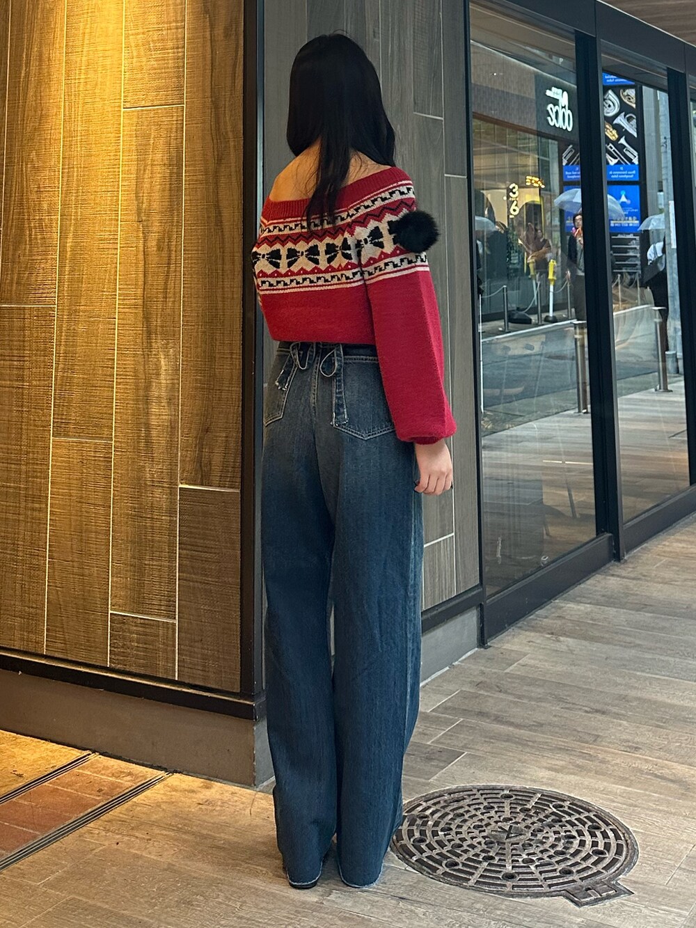 ブルー系のデニムパンツ、レッド系のニット/セーター、ブラック系のブーツを着用したレディースの秋コーディネートの4枚目の写真