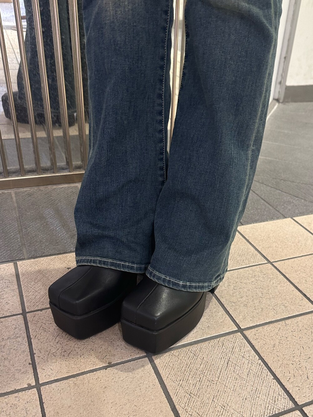 ブラック系のショルダーバッグ、ブルー系のデニムパンツ、ブラック系のブーツを着用したレディースの秋コーディネートの8枚目の写真